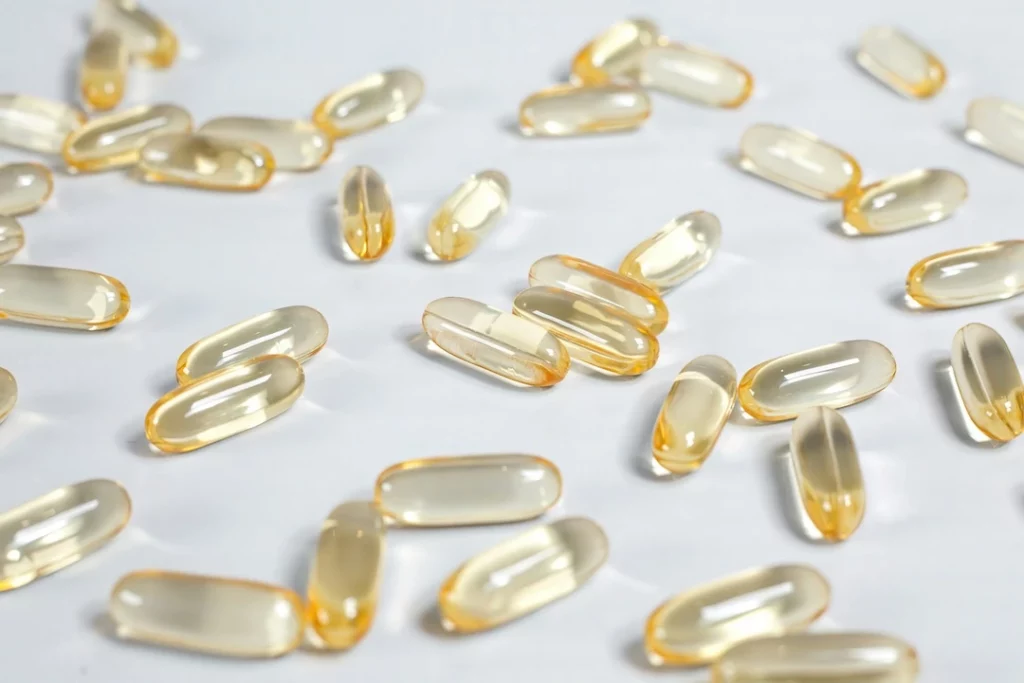 Close-up of amber soft-gel supplement capsules on a white surface