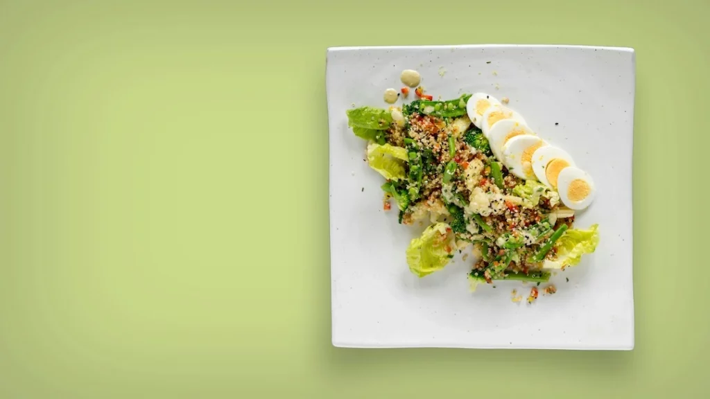 Flat-lay of eye-healthy foods: leafy greens, eggs, salmon and colourful vegetables