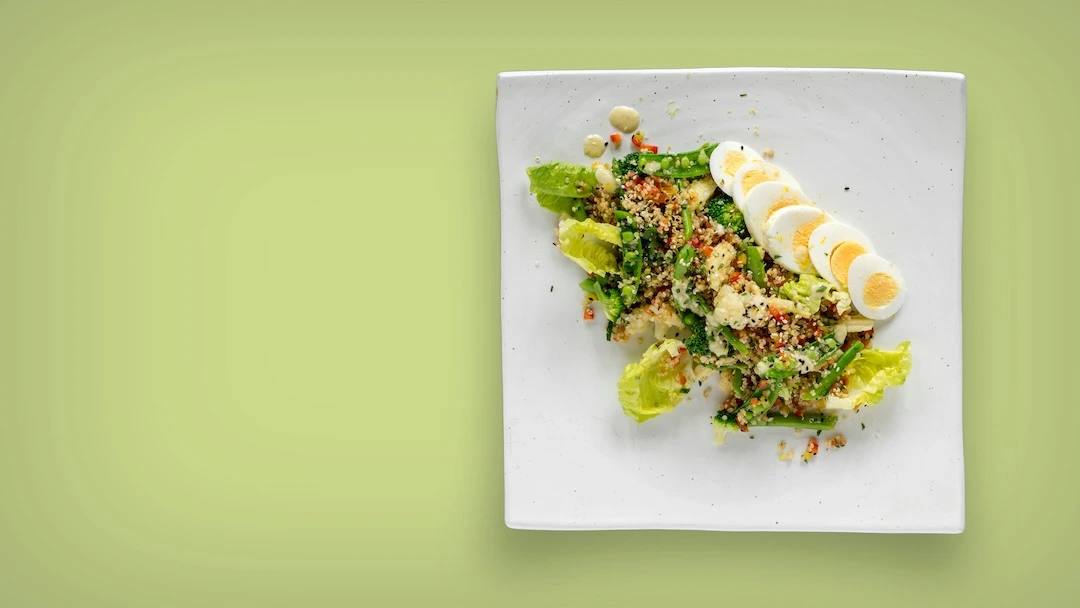 Flat-lay of eye-healthy foods: leafy greens, eggs, salmon and colourful vegetables